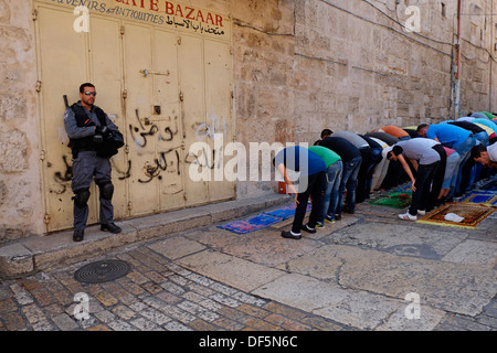 Armato di confine israeliano poliziotto guardia accanto ai palestinesi di pregare e di coloro che sono stati vietati per entrare al Akza moschea per la preghiera del venerdì il quartiere musulmano della città vecchia di Gerusalemme Est Israele Foto Stock