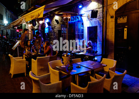 Persone che siedono all'aperto in bar allineati in Rivlin Street in Nahalat Shiva un antico quartiere cortile nel centro di Gerusalemme Ovest Israele Foto Stock