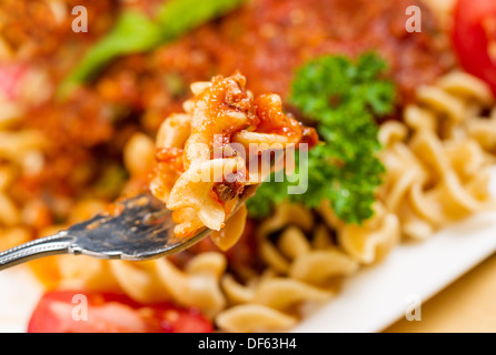 Closeup foto orizzontale di pasta fresca in una forcella circondato da cuocere la pasta ricci tagliatelle, salsa di pomodoro, prezzemolo Foto Stock