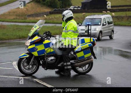 Una motocicletta di polizia funzionario di traffico dirigere il traffico a un blocco stradale Foto Stock