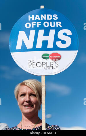 Manchester, Regno Unito. 29 settembre 2013. Una donna nel suo degli anni quaranta o cinquanta holding aloft una lettura del segno "Giù le mani dai nostri NHS' durante un Nord Ovest TUC marzo organizzata e rally che intendono difendere il servizio sanitario nazionale (NHS) i posti di lavoro e servizi da tagli e privatizzazione. Il mese di marzo coincide con il Congresso del Partito Conservatore 2013 che si terrà nella città. Credito: Russell Hart/Alamy Live News. Foto Stock