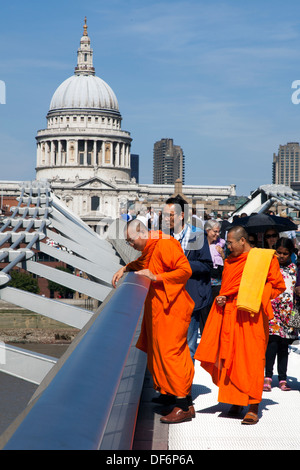 I monaci buddisti sul Millennium Bridge con la Cattedrale di St Paul in background, Londra, Inghilterra, Regno Unito. Foto Stock