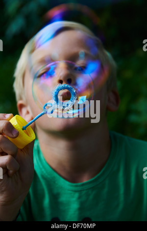 Bambino ragazzo biondo di soffiatura e facendo le bolle per esterno Foto Stock