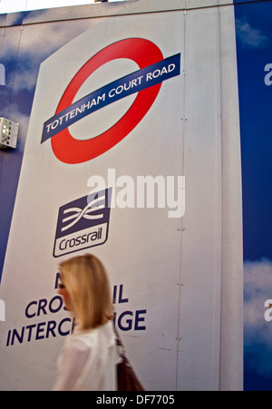 Donna che cammina oltre Tottenham Court Road Crossrail opere segno, Oxford Street, London, England, Regno Unito Foto Stock