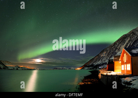 Rosso di capanne di pesca sul fiordo in inverno con luci del nord, Sommeroya, Tromsø, ‪Troms, Norvegia settentrionale, Norvegia Foto Stock