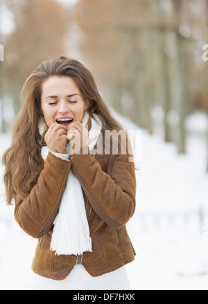 Giovane donna mani di riscaldamento in inverno all'aperto Foto Stock