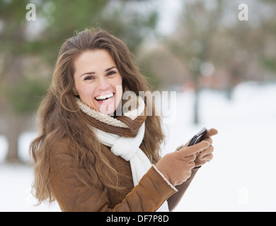 Sorridente ragazza con un telefono cellulare in inverno all'aperto Foto Stock