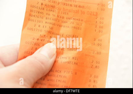 La donna il controllo dei prezzi di shopping guardando fino a ricevimento fattura dal supermercato che mostra i risparmi multisave Foto Stock