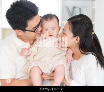 Asian genitori baciare bambino di sei mesi la ragazza a casa. Foto Stock