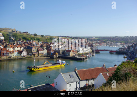 Whitby harbour con il ponte girevole cottages sul lato est della città di marine e di una draga ad aspirazione di sabbia nel fiume Foto Stock