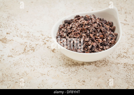 Piccolo vaso in ceramica di cacao grezzo naselli contro una piastrella ceramica sfondo con una copia spazio Foto Stock