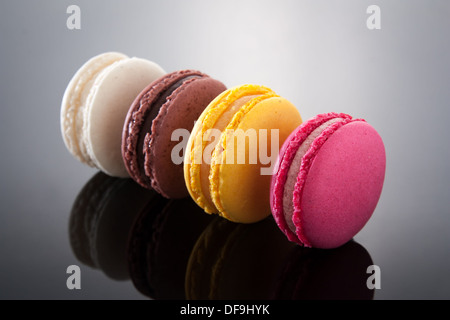 Deliziosi macarons di diversi sapori e colori sul gradiente dello sfondo Foto Stock