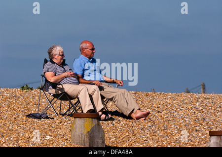 Vista frontale di una coppia di anziani seduti su sedie da spiaggia Foto Stock