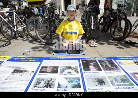 I membri della setta Falun Gong o Falun Dafa sedersi nella posizione del loto meditando in segno di protesta nel centro di Londra, Regno Unito. Foto Stock