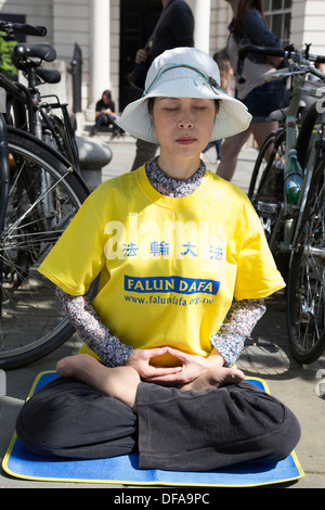 I membri della setta Falun Gong o Falun Dafa sedersi nella posizione del loto meditando in segno di protesta nel centro di Londra, Regno Unito. Foto Stock