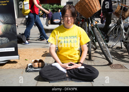 I membri della setta Falun Gong o Falun Dafa sedersi nella posizione del loto meditando in segno di protesta nel centro di Londra, Regno Unito. Foto Stock