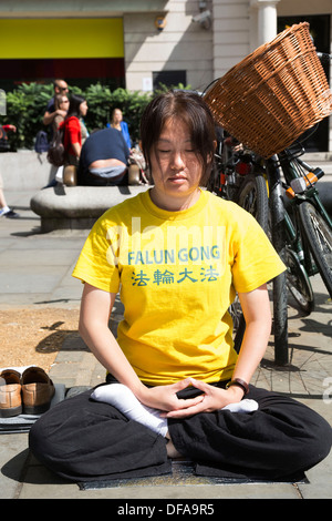 I membri della setta Falun Gong o Falun Dafa sedersi nella posizione del loto meditando in segno di protesta nel centro di Londra, Regno Unito. Foto Stock