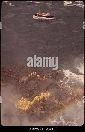 I turisti che indossano un orecchio giallo alla Grotta dei venti, situata alla base delle scogliere di Boat Island, osservano le caratteristiche naturali della zona. Foto Stock