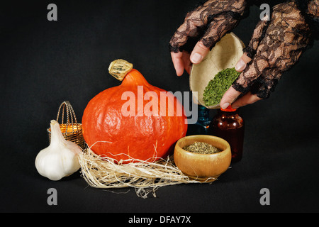 Strega preparazione mix di erbe per la festa di Halloween in dark room Foto Stock