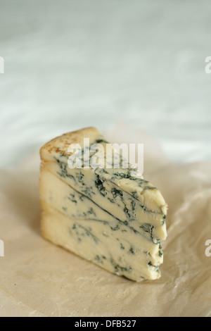 Del formaggio Stilton su di età compresa la carta pergamena shot con molto poco profondo di messa a fuoco selettiva sul bordo anteriore in alto Foto Stock