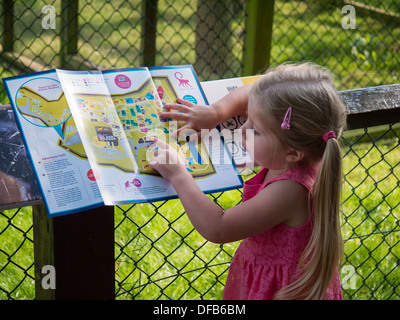 Una bambina la lettura di una mappa su un viaggio di una giornata allo Zoo. Foto Stock