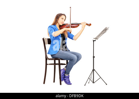 Giovane donna su una sedia di legno a suonare il violino Foto Stock