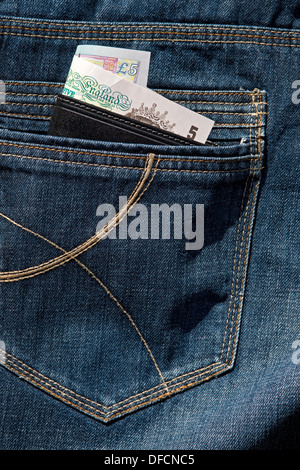 Primo piano di un portafoglio in pelle che mostra banconote in contanti inglesi nella tasca posteriore di jeans in denim e che porta al borseggiamento in Inghilterra e Regno Unito Foto Stock