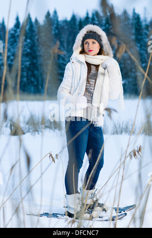 Inverno, donna con le racchette da neve in posa dietro le lamelle, formato verticale Foto Stock
