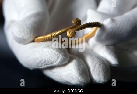 A più di tremila anni di golden anello giace sul guanto di un archeologo nel deposito dell'Ufficio statale per la cultura e la conservazione dei monumenti storici in Wiligrad, Germania, 02 ottobre 2013. La gioielleria in oro è stato ritrovato in una tomba in un campo vicino a Crivitz; uno dei più ricchi Età del Bronzo tombe che si trovavano nella zona negli ultimi cento anni. Foto: Jens BUETTNER Foto Stock