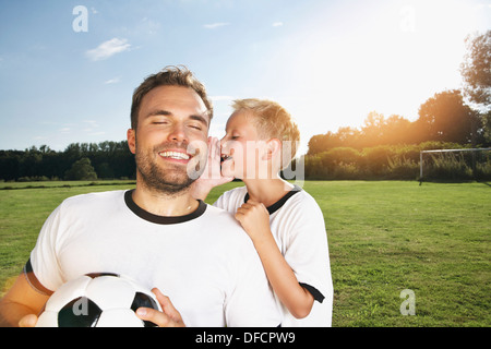 Germnay, Colonia, figlio whispering in padre l orecchio Foto Stock