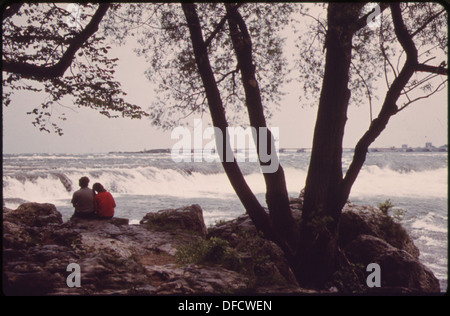 Una coppia gode della vista delle rapide del fiume Niagara da Goat Island, che separa il lato americano e canadese delle Cascate del Niagara. Questa posizione panoramica è famosa per la sua bellezza naturale mozzafiato. Foto Stock
