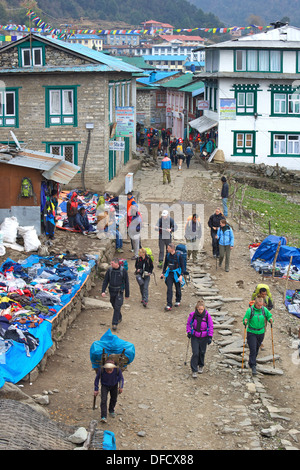 Il trekking e i portieri a piedi attraverso la città di Lukla, in rotta verso il Campo Base Everest trek, Nepal, Asia Foto Stock