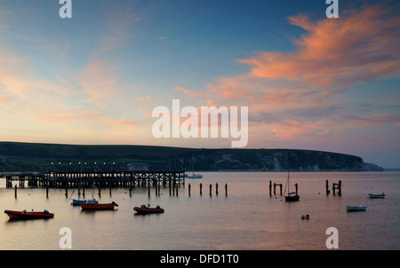 UK,Dorset,Swanage,Tramonto su Ballard punto, vecchio e nuovo molo in Swanage Bay Foto Stock