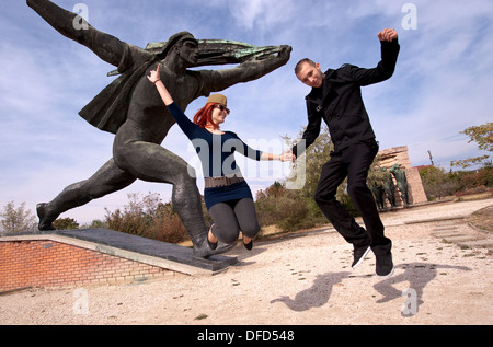 Ungherese di uomo e donna che si tuffa nella parte anteriore del monumento mentre visitano Memento Parco delle Statue di Budapest, in Ungheria Foto Stock