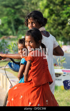 Tre poveri villaggio indiano bambini in sella ad una bicicletta. Andhra Pradesh, India Foto Stock