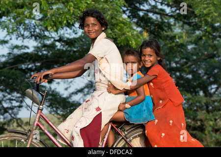 Tre poveri villaggio indiano bambini in sella ad una bicicletta. Andhra Pradesh, India Foto Stock