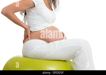 Donna incinta seduta sul montare la sfera con la mano sulla sua schiena, isolato Foto Stock