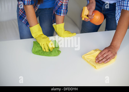 Close-up di maschi e femmine di pulizia delle mani la superficie del tavolo con strofinacci e detergente Foto Stock