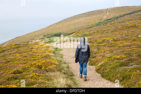 Donna che indossa kagoule camminando lungo la costa sud occidentale percorso in corrispondenza di Sant Agnese testa, Cornwall, Inghilterra Foto Stock