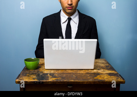 Giovane imprenditore a bere caffè e lavorare sul suo computer portatile Foto Stock