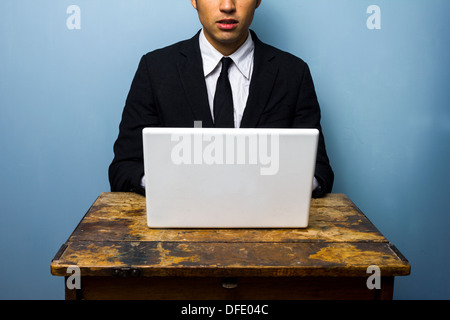 Giovane imprenditore è seduta su una vecchia scrivania e lavorare sul suo computer portatile Foto Stock