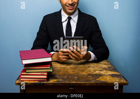 Giovane imprenditore preferisce leggere su un tablet piuttosto che i libri Foto Stock