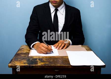 Giovane imprenditore è seduta su una vecchia scrivania e la firma di un contratto Foto Stock