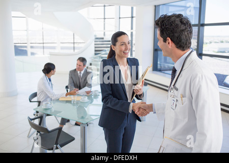 Medico e imprenditrice handshaking in riunione Foto Stock