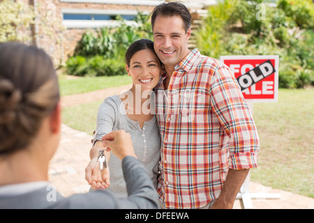 Agente immobiliare dando giovane le chiavi di casa nuova Foto Stock