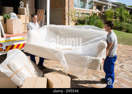 Movers trasportare divano dal movimento van nel viale di accesso Foto Stock