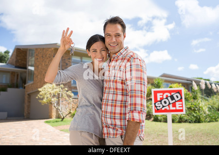 Ritratto di Coppia sorridente tenendo premuto i tasti nella parte anteriore della nuova casa Foto Stock