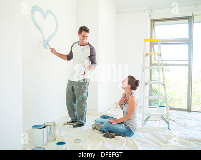 Donna Uomo guarda la vernice cuore blu sulla parete Foto Stock