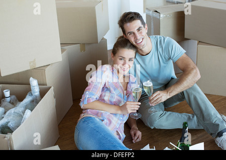 Ritratto di giovane gustando champagne tra scatole di cartone Foto Stock