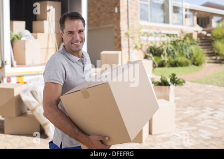 Ritratto di uomo che porta una scatola di cartone da van in movimento Foto Stock